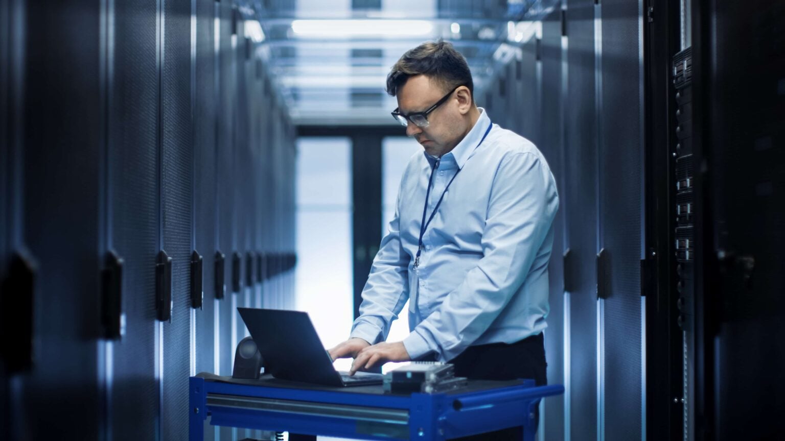 An engineer working on a laptop in a server room