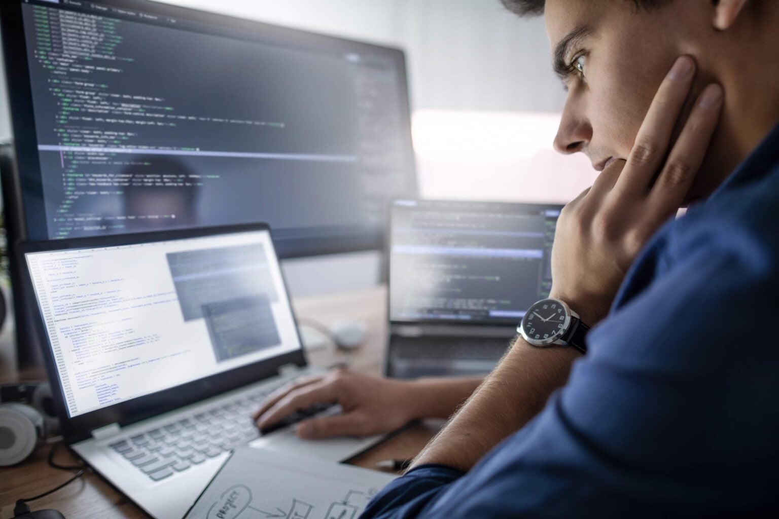 A developer working on code across two screens
