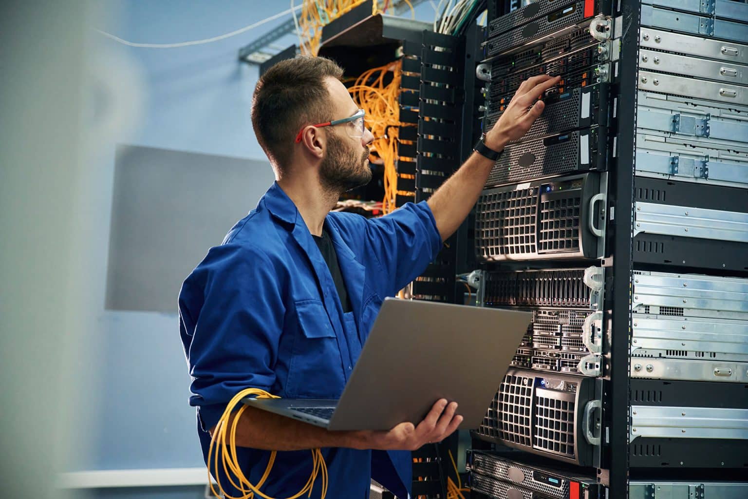 An engineer with a laptop working at a server rack