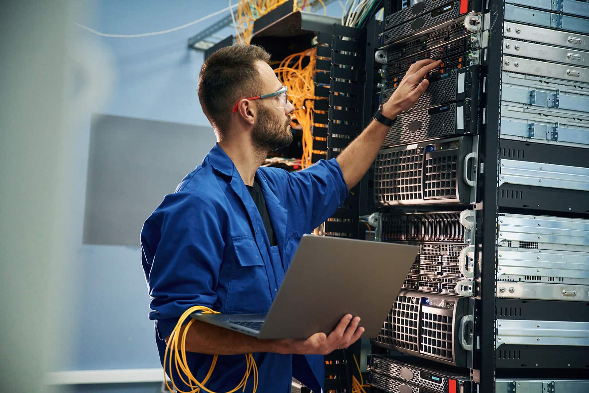 Engineer with a laptop working at a server rack