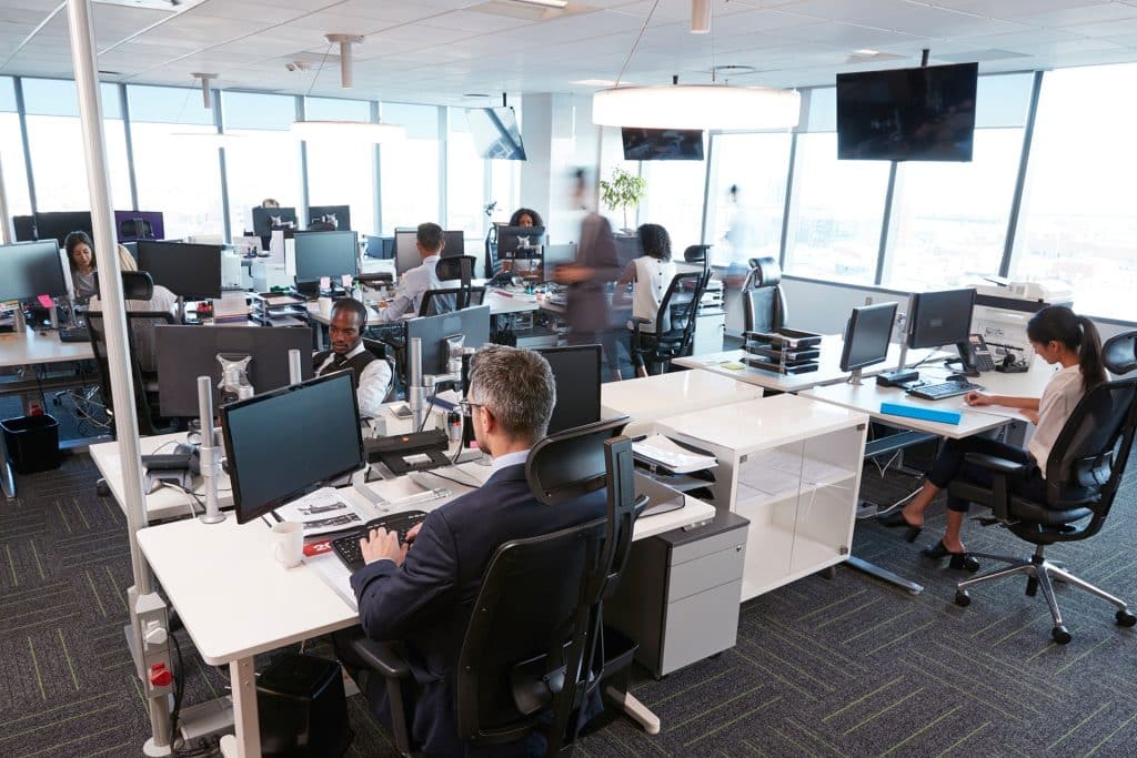 A busy open plan office with staff at their desks