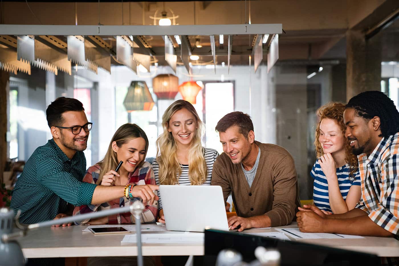 A team gathered around a laptop in a bright office