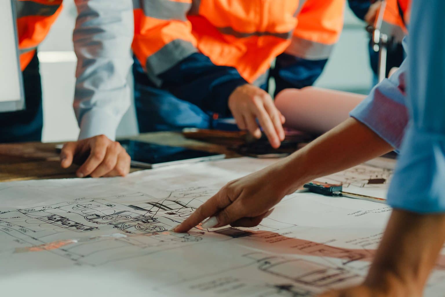 Engineers pointing at drawings spread across a table