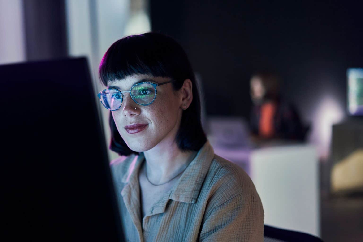 A woman in glasses focused on a screen