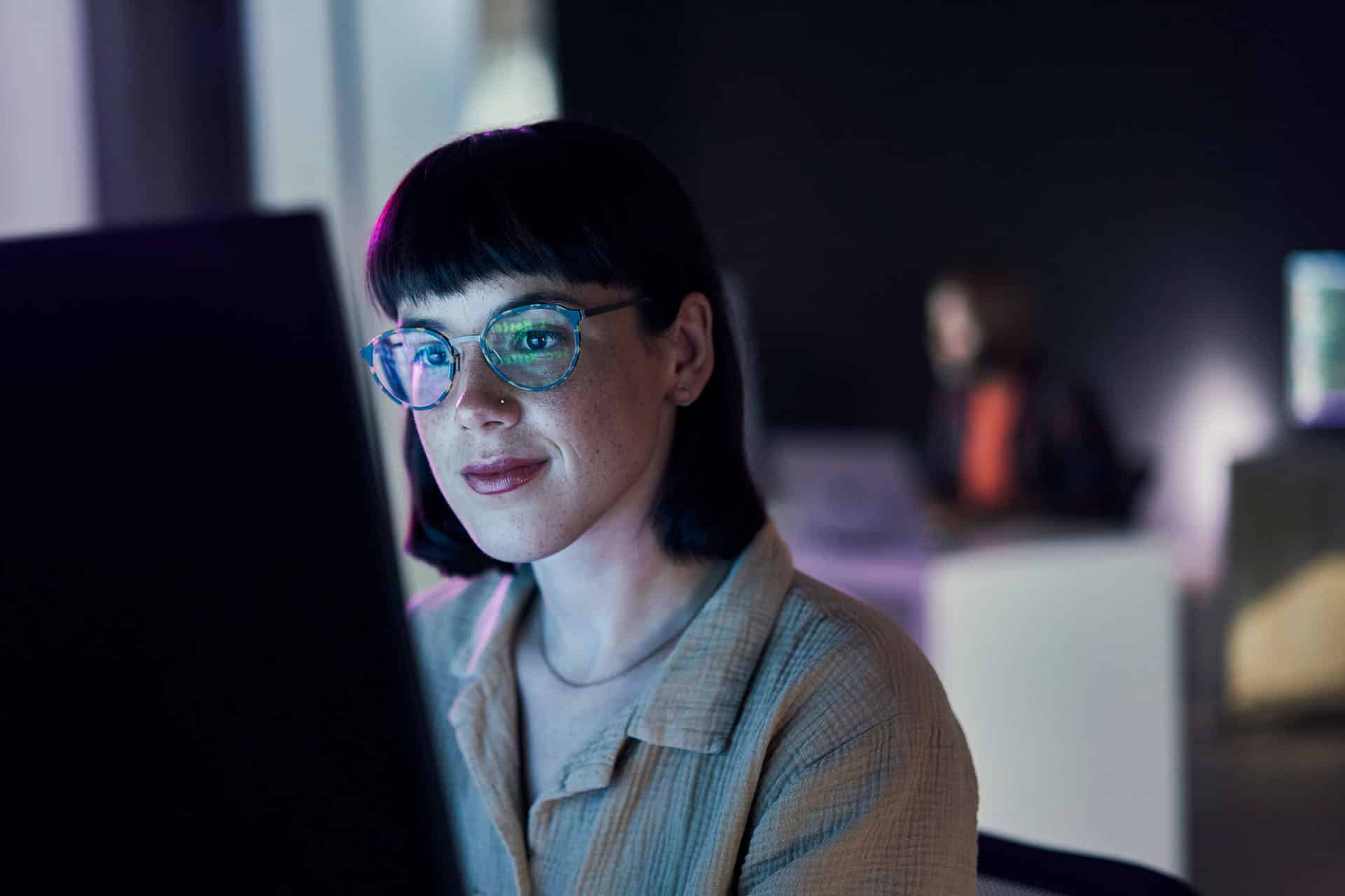 Woman in glasses focused on a screen