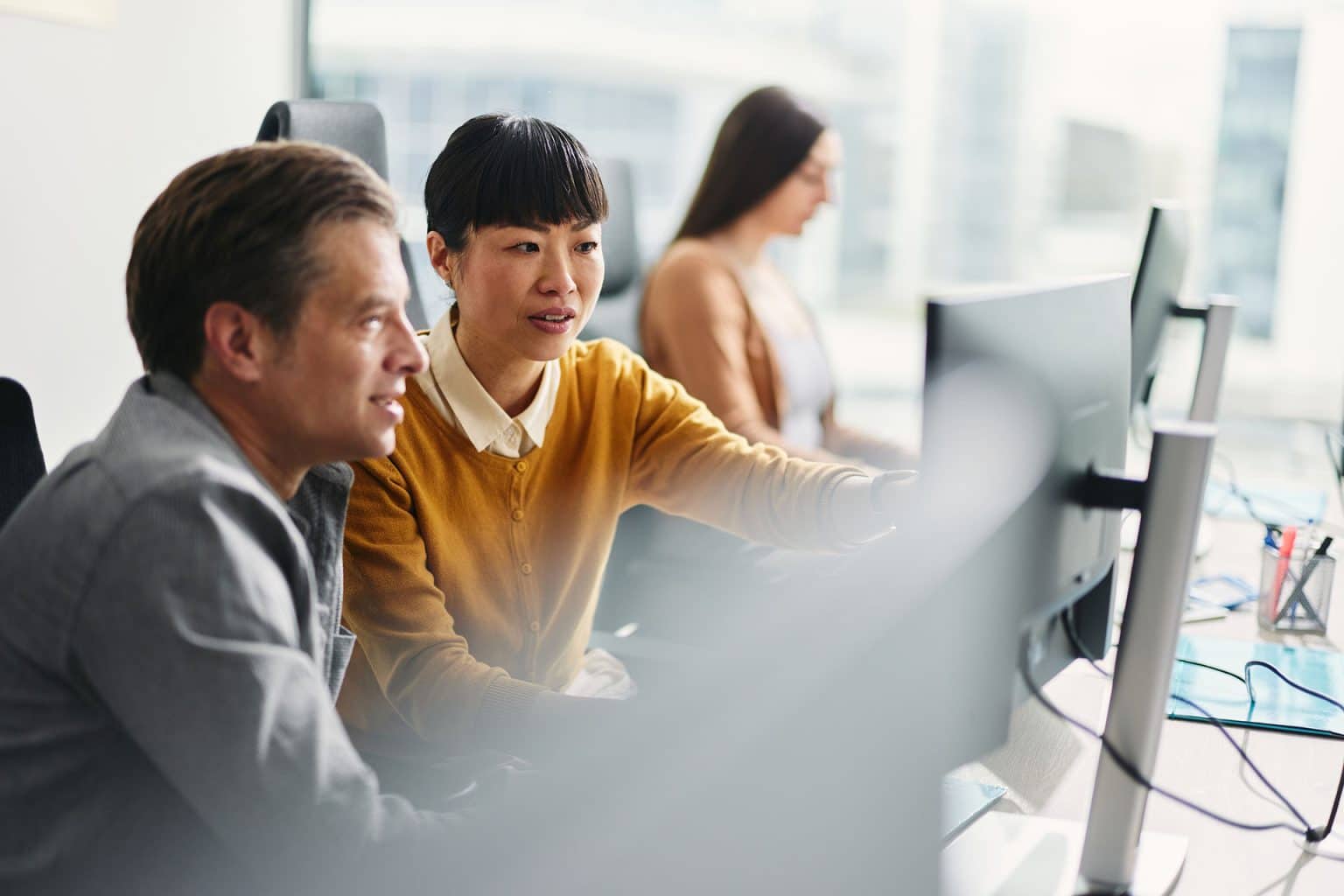 Three colleagues working together at a computer