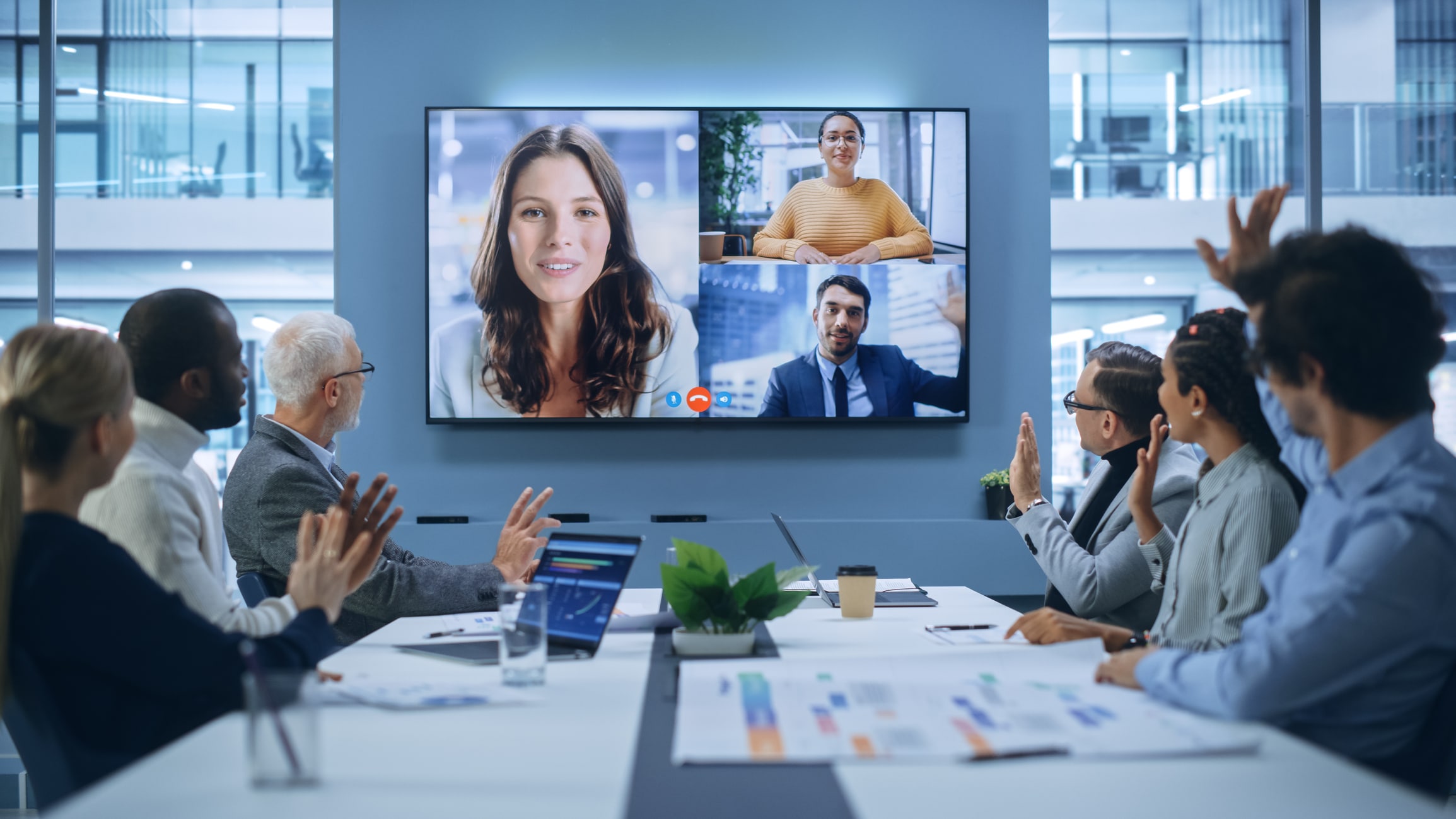 Team in a meeting room on a video call with remote colleagues