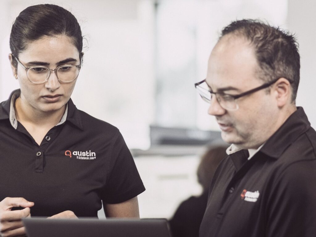 Two Austin Technology engineers reviewing a plan on a laptop