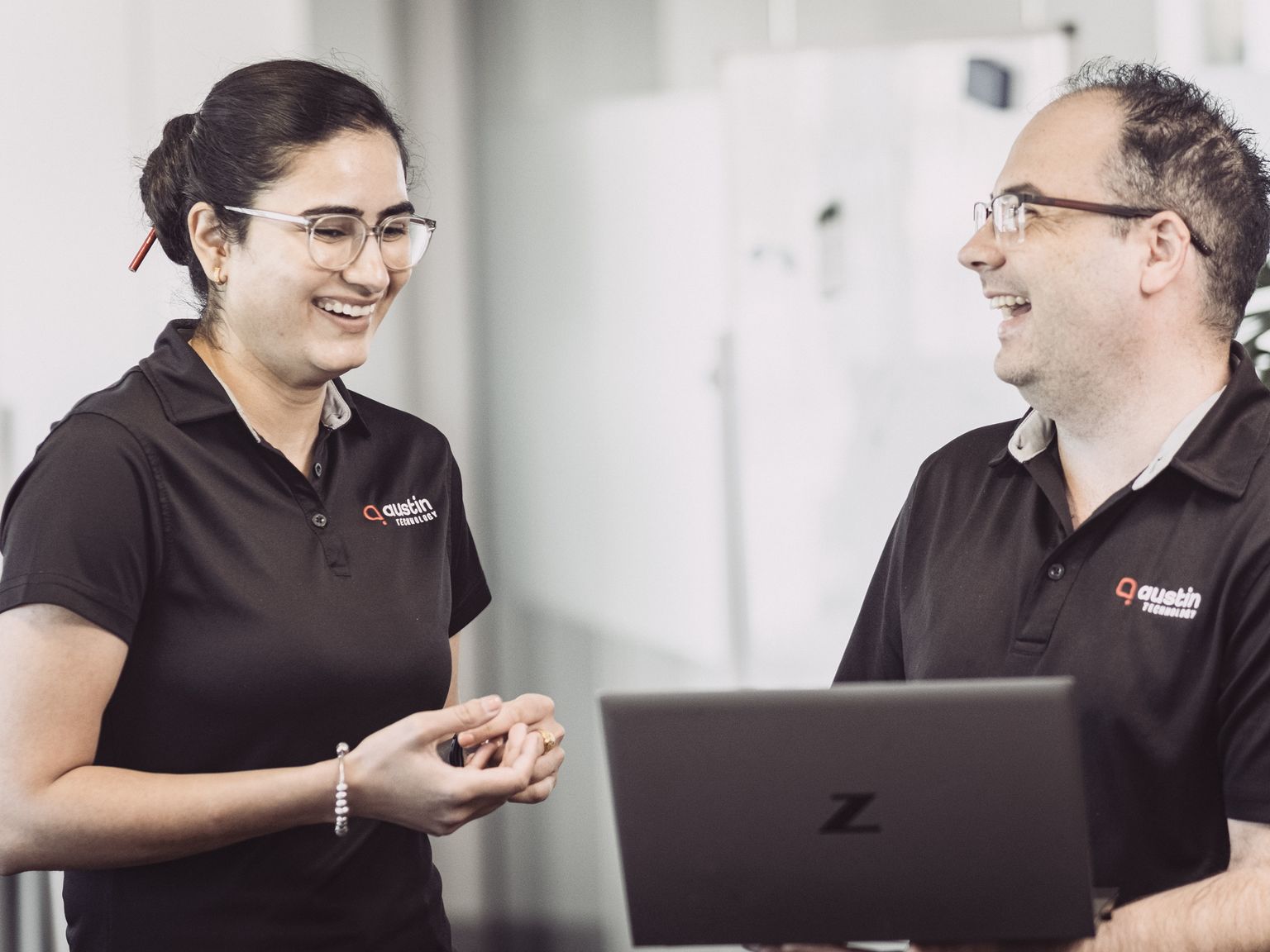Two Austin Technology engineers laughing while they work through a laptop