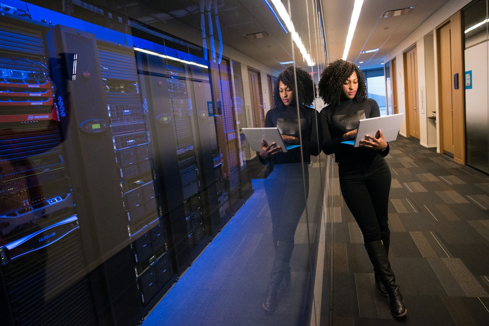 Two colleagues with a laptop walking past a glass walled server room