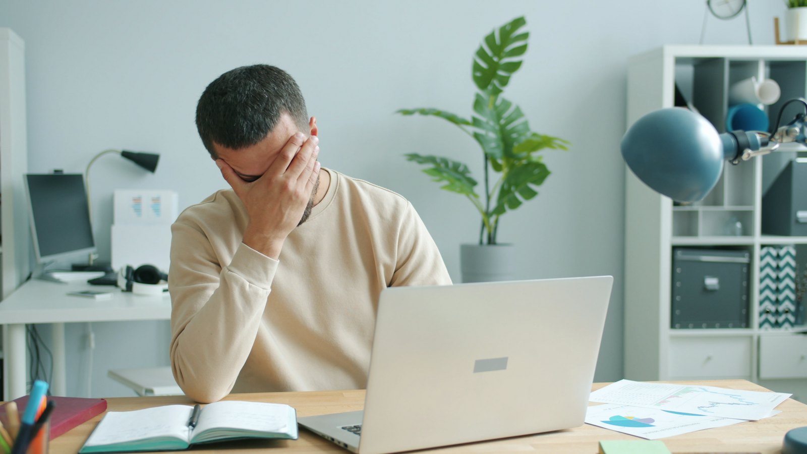 Man rubbing his face in front of a laptop