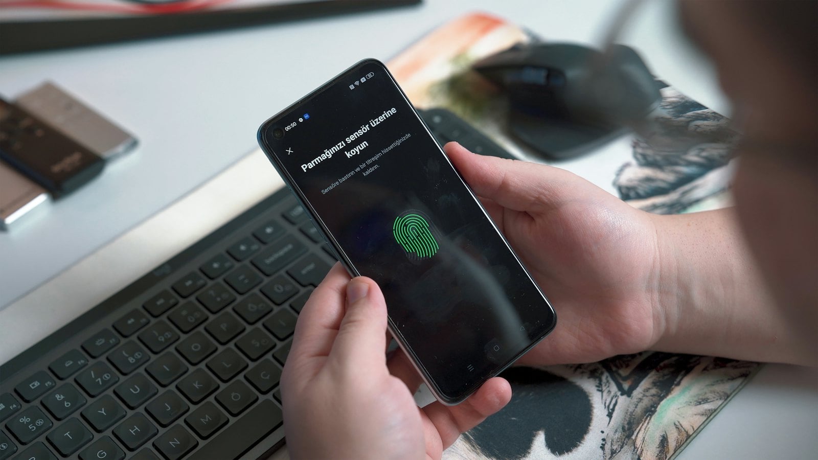 Person approving a sign in with a fingerprint on a phone beside a keyboard