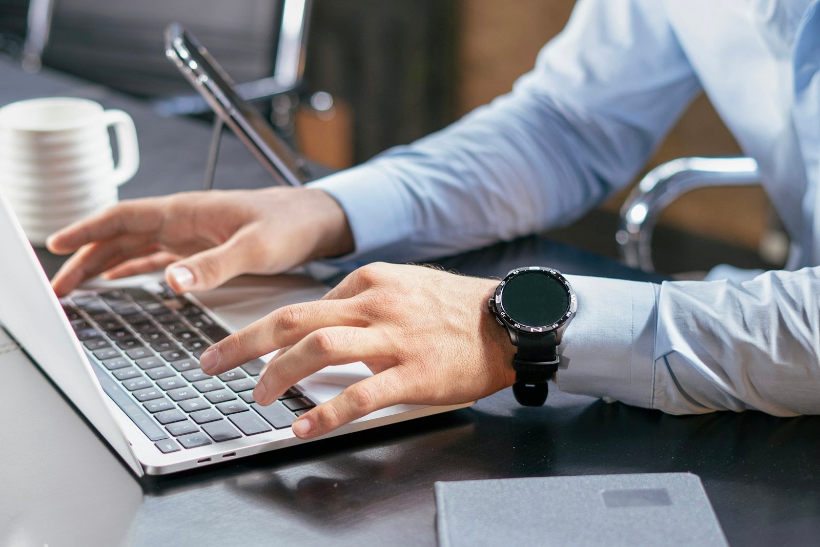 Hands typing on a laptop at an office desk