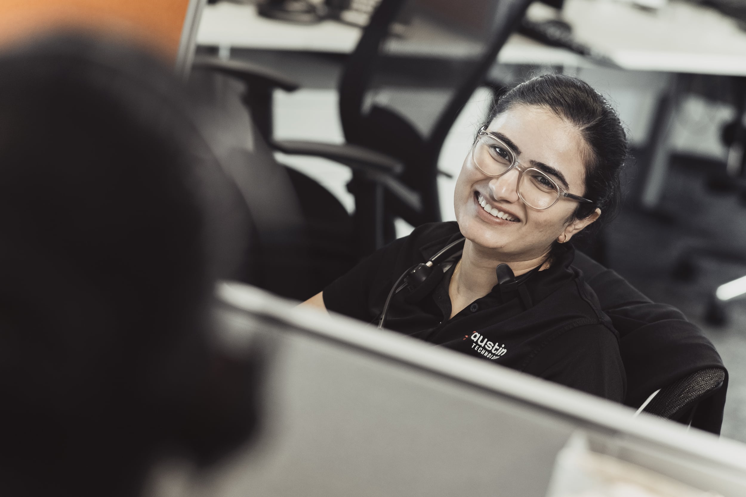 An Austin Technology service desk engineer smiling on a call at her desk