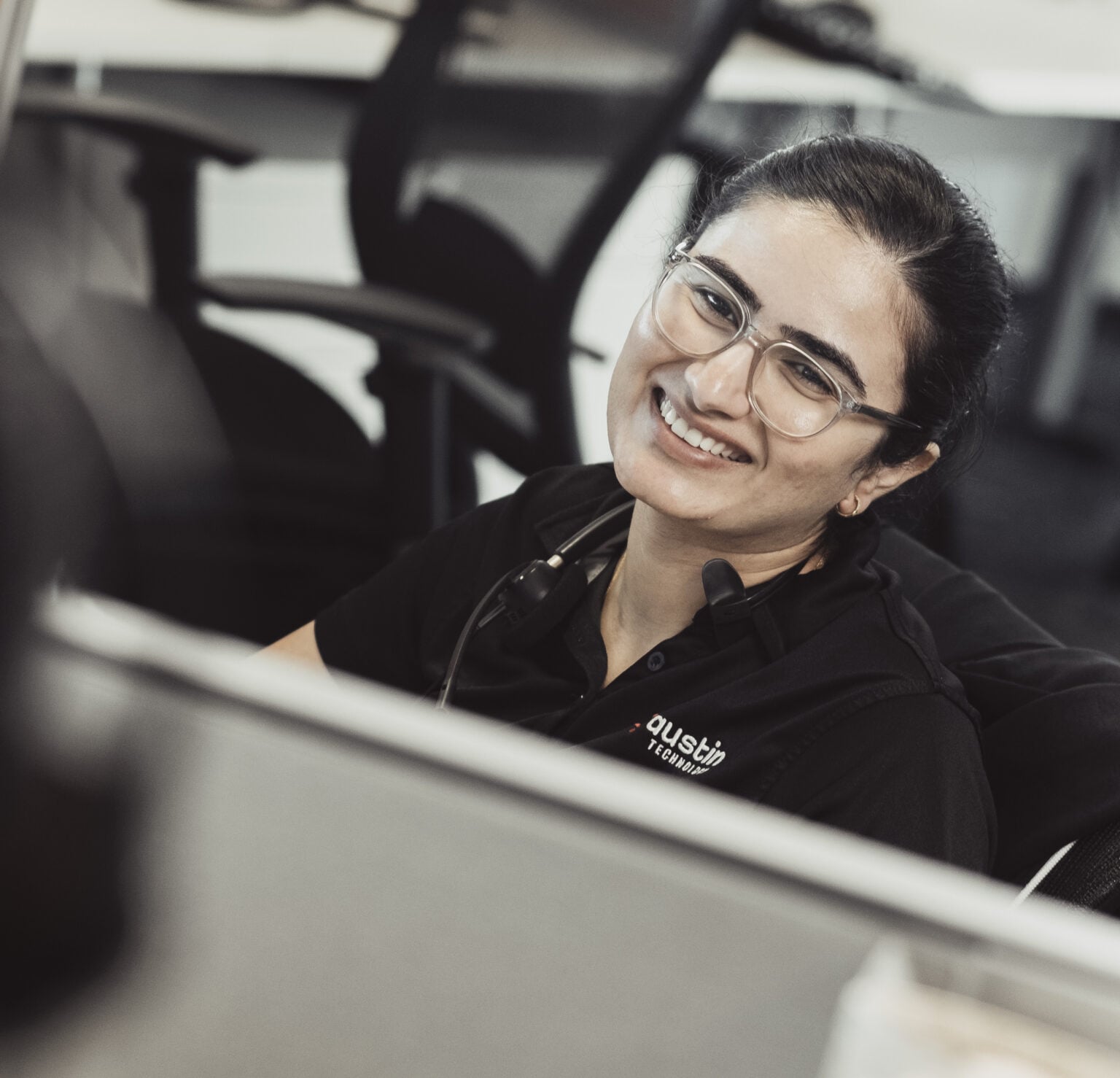 An Austin Technology engineer smiling at her desk