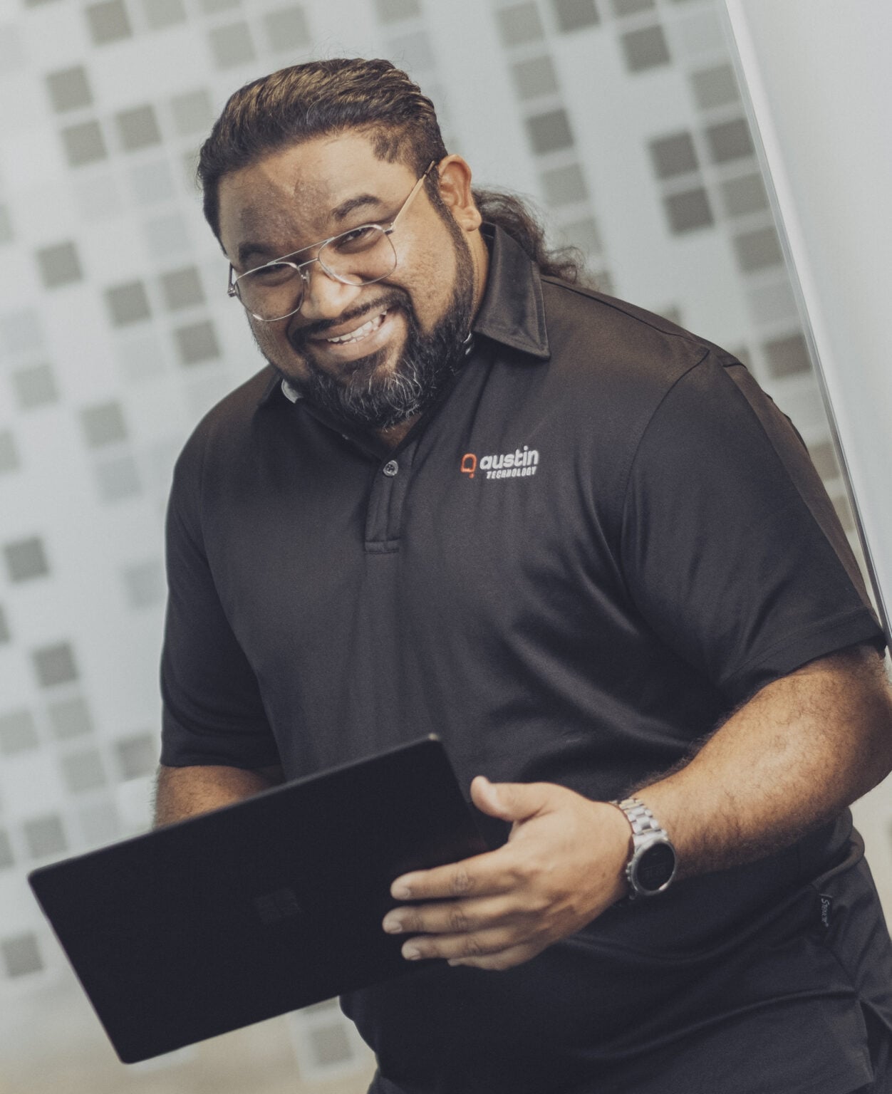 An Austin Technology consultant smiling as he brings a tablet over to a client