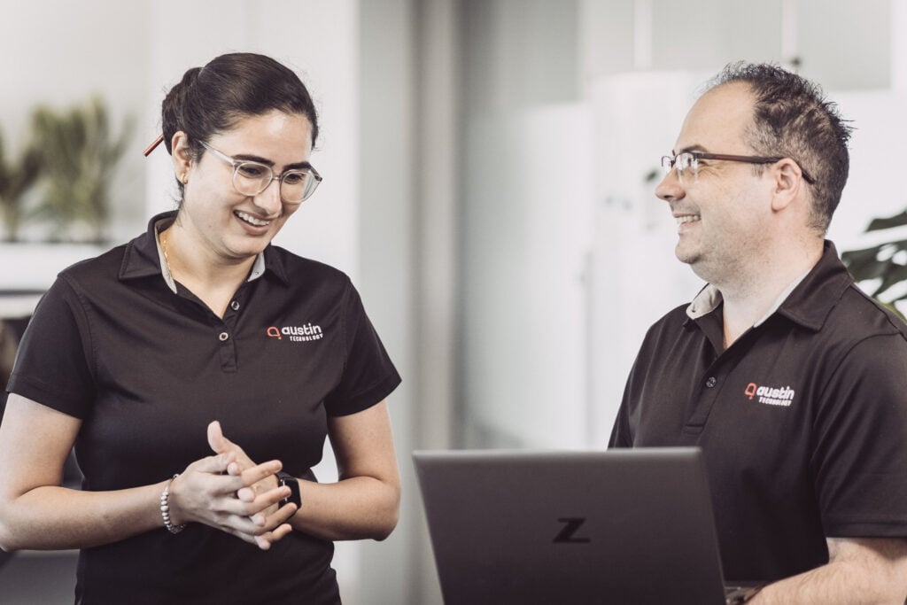 Two Austin Technology consultants laughing over a laptop while they plan a change