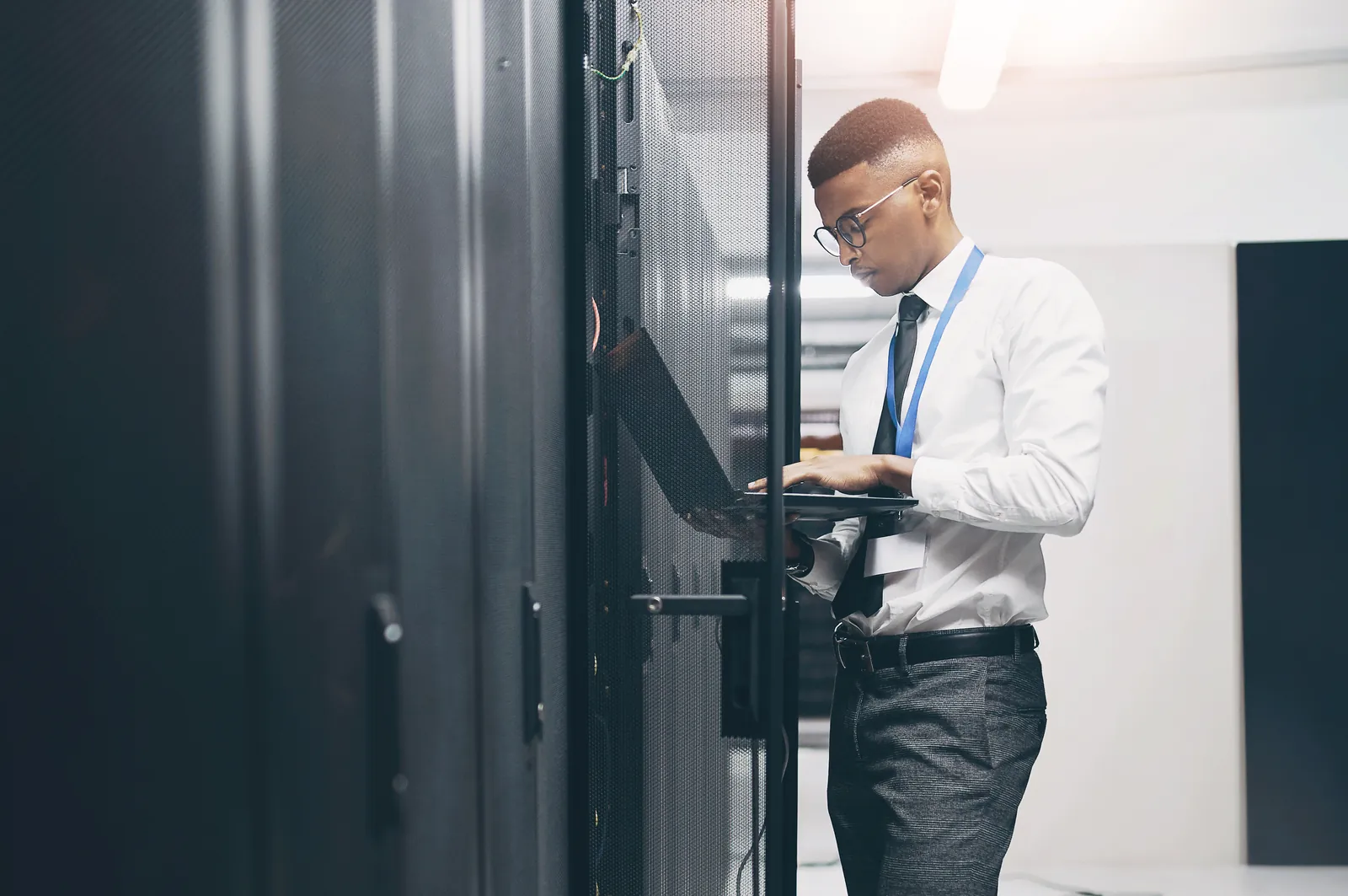 An engineer working on a laptop at an open server cabinet