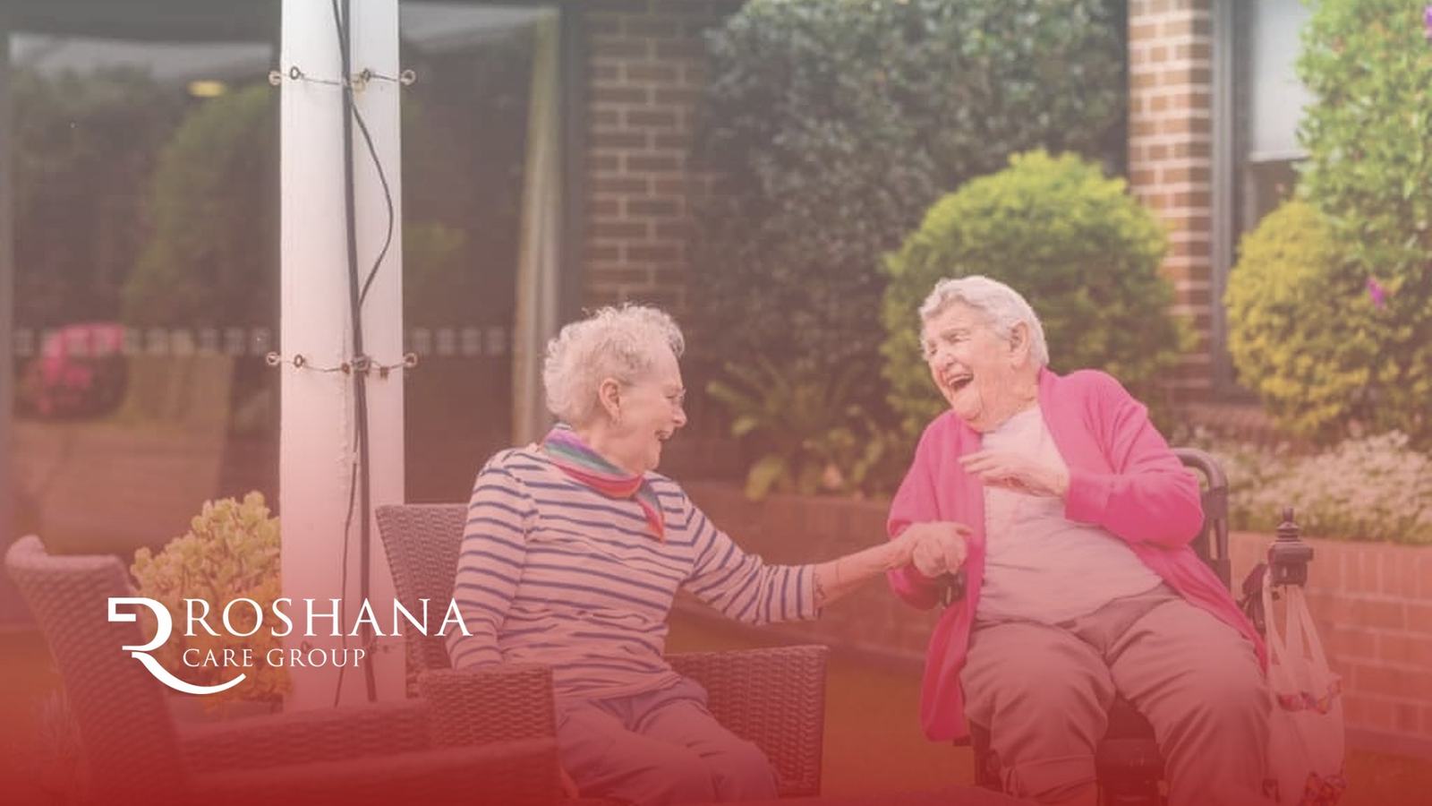 Two Roshana Care Group residents laughing together in a garden courtyard
