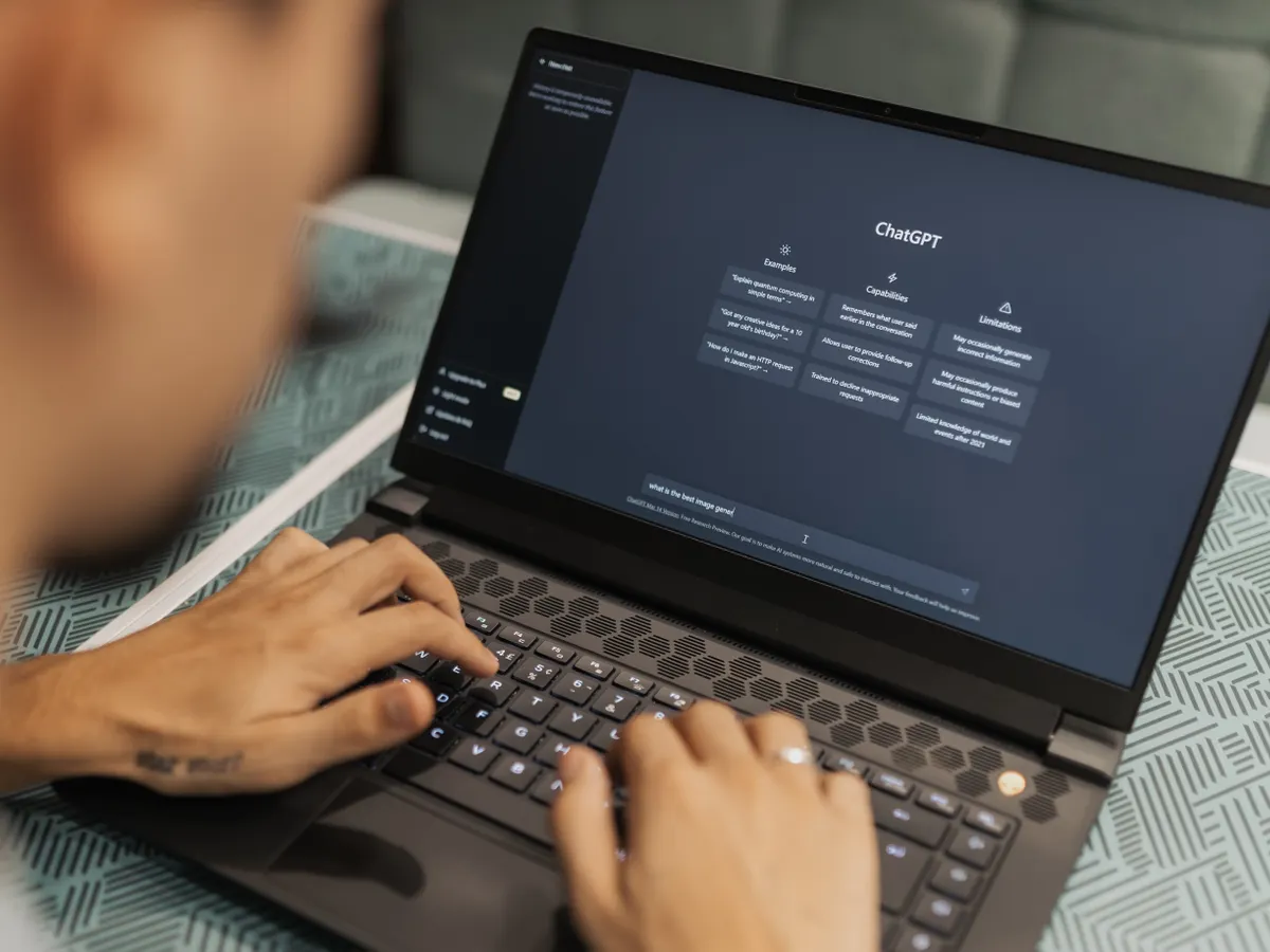 Someone typing a prompt into an AI assistant on a laptop