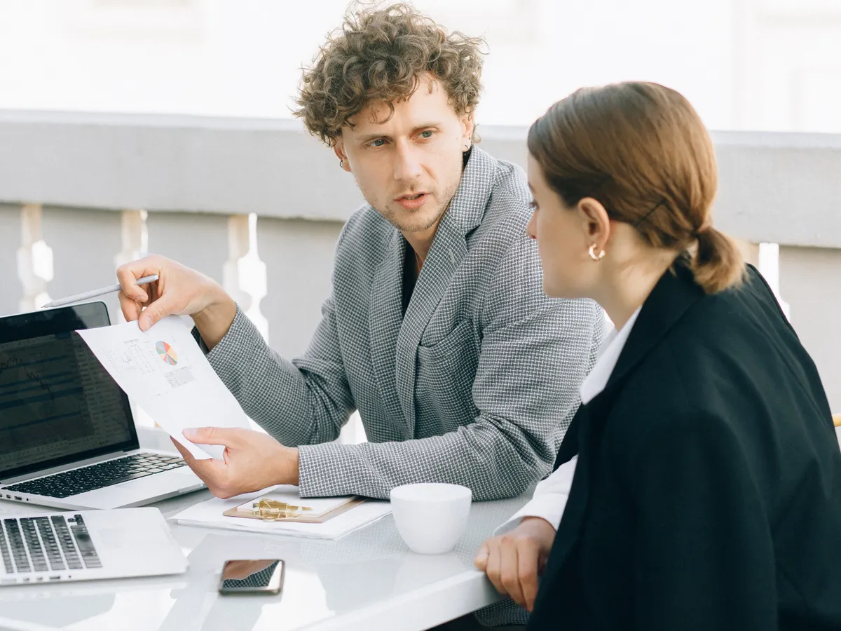 An IT manager and a colleague talking through a plan at a laptop