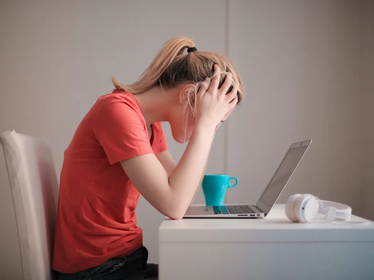A frustrated office worker with her head in her hands at a laptop
